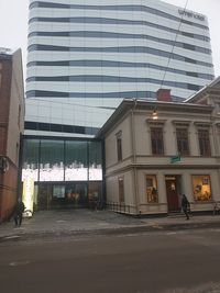 Street by buildings in city against sky