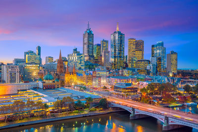 Illuminated modern buildings in city against sky