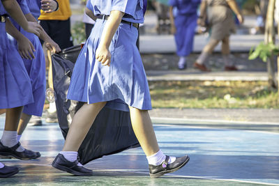 Low section of schoolgirls holding plastic bag walking outdoors