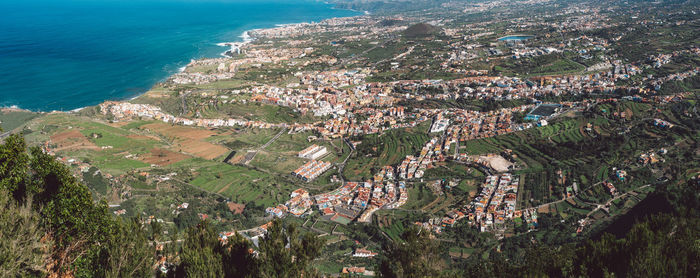 High angle view of city buildings and trees by sea