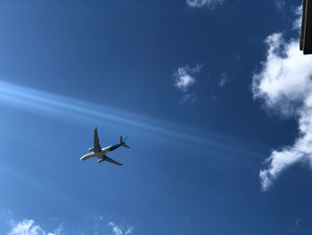 Low angle view of airplane flying against blue sky