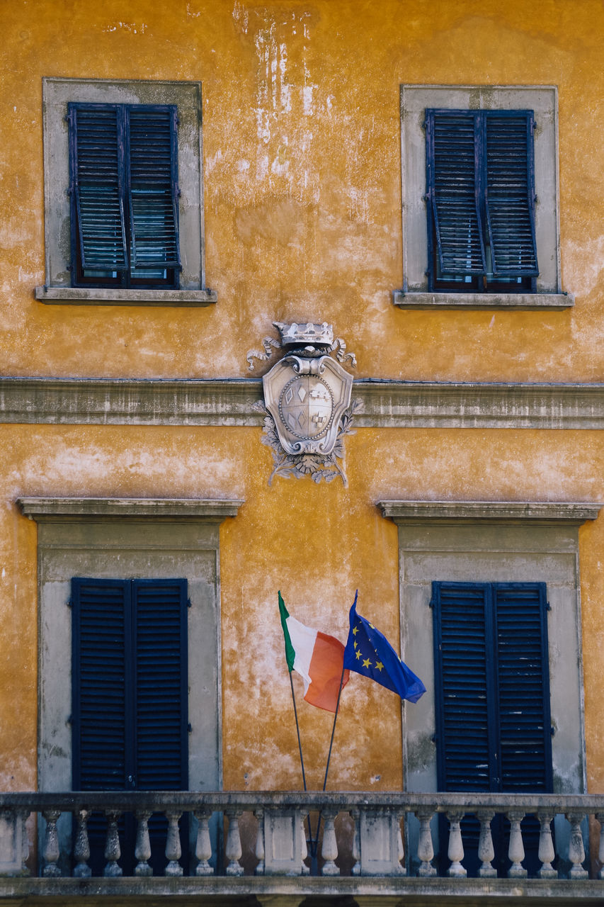 architecture, building exterior, window, wall, built structure, blue, facade, house, no people, building, urban area, day, city, outdoors, street, residential district, old, wall - building feature, home, brick, history, road, the past, flag, closed