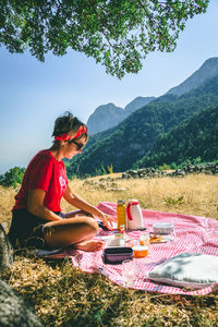 Woman sitting on grassy field by mountains