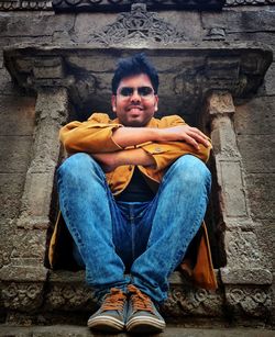 Portrait of man sitting against wall