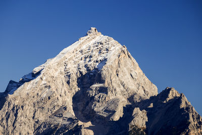 Low angle view of snowcapped mountain against clear blue sky