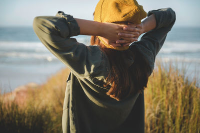 Rear view of woman standing by sea against sky