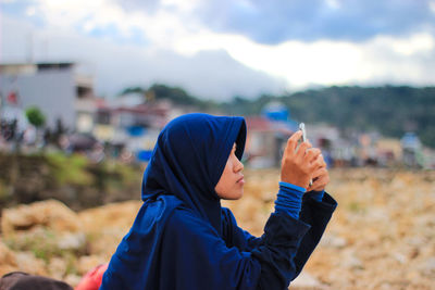 Midsection of woman holding mobile phone outdoors