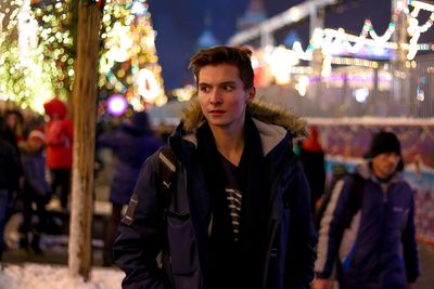 Young man standing at amusement park during night