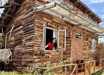 Woman looking through window from log cabin