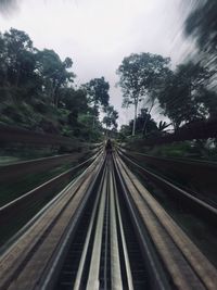 Railroad tracks by trees against sky