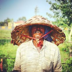 Farmer wearing asian style conical hat on field