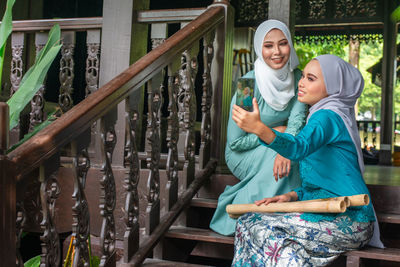 Portrait of happy friends standing against railing