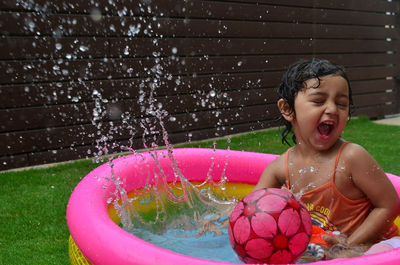 Happy girl playing in water at yard