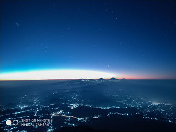 Aerial view of illuminated city against blue sky