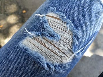 Close-up of person wearing torn jeans