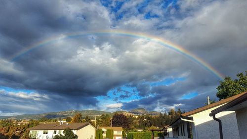 Rainbow over buildings in city against sky