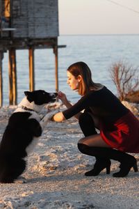 Full length of young woman playing with dog outdoors