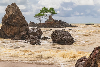 Rock formation on beach against sky