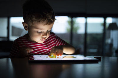 Portrait of boy holding table at home