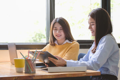 Young woman using phone while sitting on table