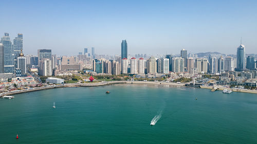 High angle view of city by sea against clear blue sky