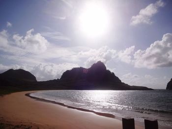 View of calm beach against cloudy sky