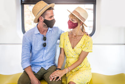 Smiling couple wearing flu mask sitting in train