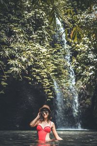 Woman standing by waterfall in forest