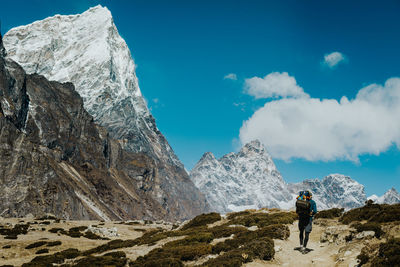 Rear view of man walking on rock against sky