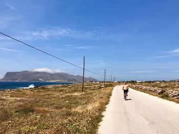 Rear view of man walking on road against sky