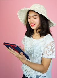 Beautiful young woman using smart phone against gray background
