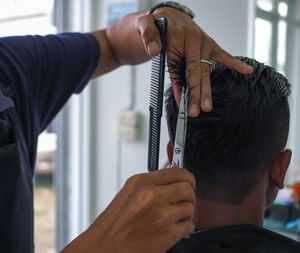 Cropped hands of hairdresser cutting man hair