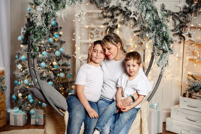 Portrait of young woman standing against christmas tree