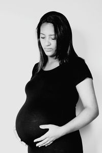 Pregnant woman standing against white background