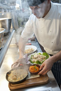 Chef preparing hot dish at commercial kitchen in british pub