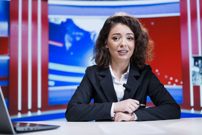 Portrait of smiling businesswoman using laptop while sitting on table