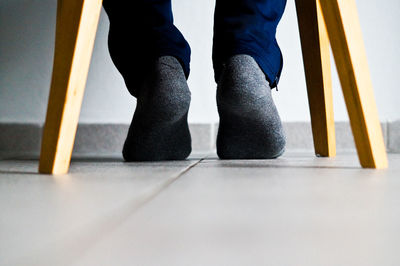 Low section of man wearing sock while sitting on table at home