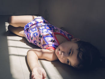 Midsection of little girl lying down on floor at home