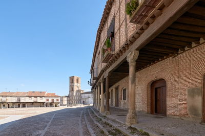 Empty road amidst buildings against sky in city