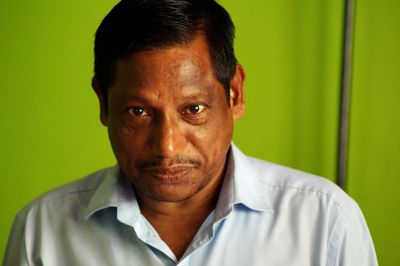 Close-up portrait of mature man standing against green curtain