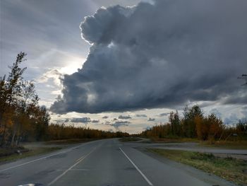 Road by trees against sky