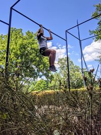 Low angle view of man jumping against trees