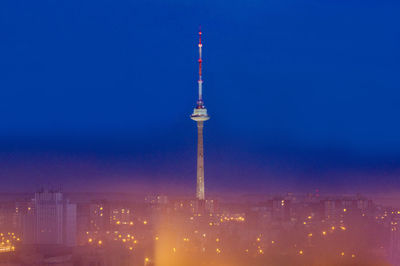 Communications tower in illuminated city at night
