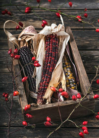 Dried corn indian cobs of different colors and rose hip branches in an old wooden box. 