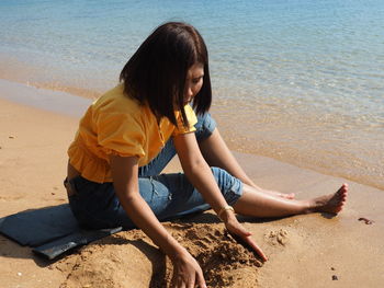 Girl sitting on shore at beach