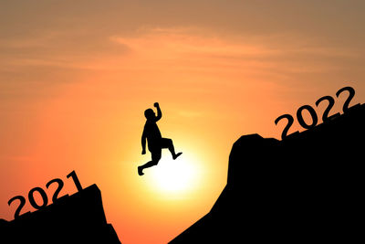 Silhouette people jumping against sky during sunset