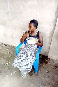 High angle view of woman sitting against wall