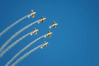 Low angle view of airshow against clear blue sky