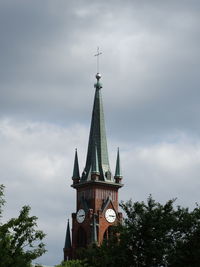 Apex of an old church with a cross in the grey sky.