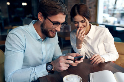 Young man using mobile phone while sitting on table